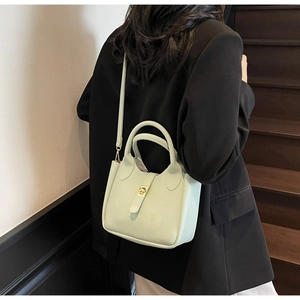 Detail view of mint green litchi grain leather bucket bag with golden turn-lock closure