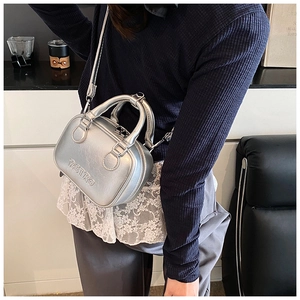 Detail view of silver metallic handbag with RETRO embossing shown on a fashion model