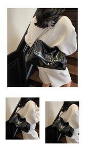 Detail of glossy black leather tote bag featuring a metallic swivel lock and chain strap