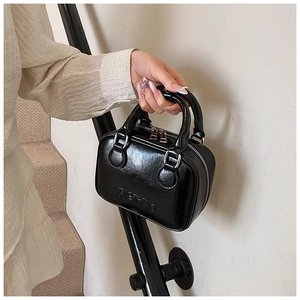 Detail of black glossy patent leather mini bag with embossed Retro text for women