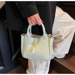 Close-up of mint green bucket bag featuring lychee grain leather and gold hardware