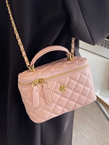 Elegant pink quilted box bag with gold floral clasp and chain strap on a black blazer