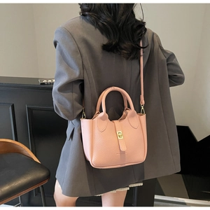 Detail of pink lychee textured leather bag with gold twist lock and top handle