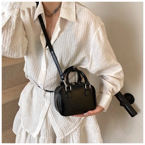 Chic black shiny leather handbag with RETRO embossing carried by model on stairs