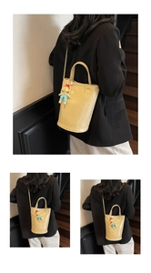 Detail van een beige PU emmertas met een schattige poppenhanger en verstelbare schouderband