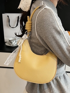 Borsa hobo minimalista in pelle gialla con fiocco in pizzo e perle indossata da una modella