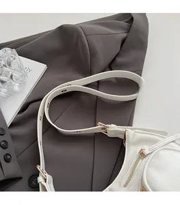 Detail view of white leather shoulder bag featuring adjustable strap with gold buckles