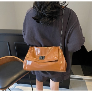 Detail view of the caramel brown leather tote bag with metallic chain strap and turn-lock