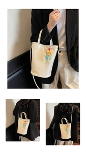 Detailweergave van de witte PU-lederen emmertas met cartoonhanger en afneembare schouderriem