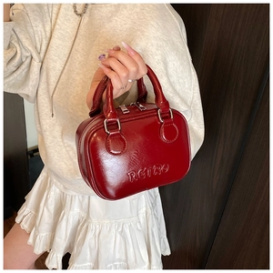 Detail of red glossy leather handbag with RETRO embossed logo and silver zipper