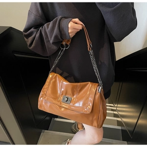 Detailed close-up of a brown PU leather tote bag featuring a metallic twist-lock closure