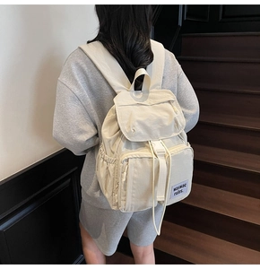 Off-white lightweight nylon backpack with multi-pocket design shown on model's back