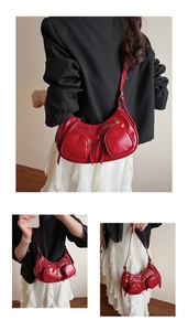 Detail view of red patent leather punk style underarm bag with silver zipper pockets