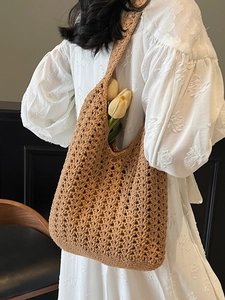 Sac cabas au crochet marron fait main avec motif ajouré porté par un mannequin en robe blanche