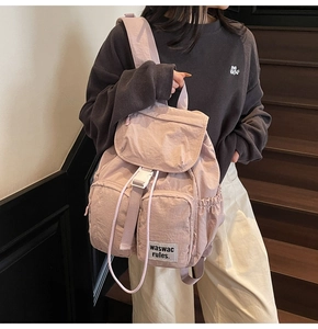 Detail view of the mauve nylon backpack with flap closure and white buckle on model