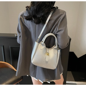 Detail of silver lychee pattern leather bucket bag with golden metal turn-lock and strap