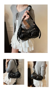 Detail view of glossy black shoulder bag with functional zip pockets and metal buckles