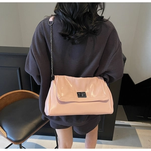 Detail view of pink patent leather tote bag with black metal twist lock and chain strap