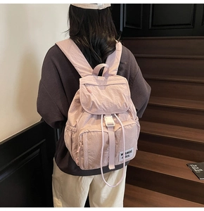 Detail of pink nylon travel backpack with drawstring closure and white buckle straps