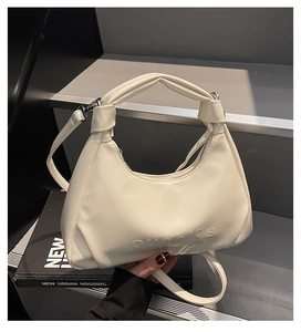 Detail of cream white half-moon bag with knotted handle and adjustable shoulder strap