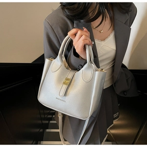 Detail showing silver litchi grain leather bag with gold twist-lock and brand logo