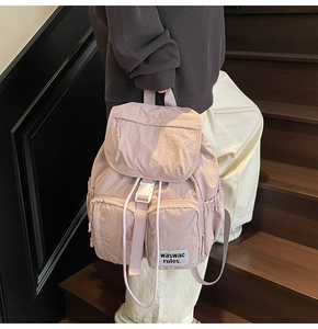 Detail of pink nylon travel backpack with drawstrings and side pockets on stairs