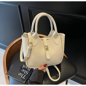 Close-up of creamy white bucket bag featuring litchi grain texture and gold twist lock
