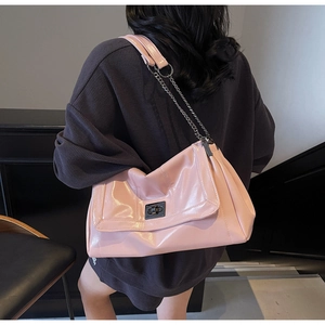 Detail view of pink glossy shoulder bag with metal chain strap and turn-lock closure