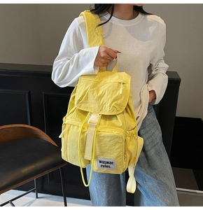 Close-up of bright yellow nylon backpack featuring white buckles and side zipper pockets