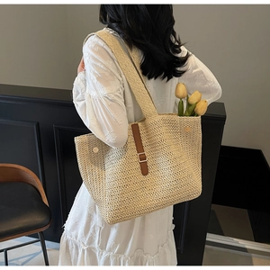 Détail d'un grand sac cabas en paille tressée avec sangle en cuir marron et boucle