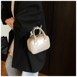 Retro style cream mini handbag with embossed lettering held by model for commute