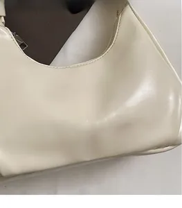 Close-up of cream white waxed leather handbag with embossed logo and metal zipper closure