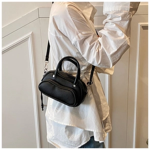 Close-up of black lychee grain leather crossbody bag with dual zippers and long strap