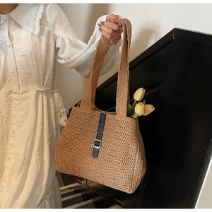 Détail d'un sac cabas en paille tissée avec boucles en cuir noir et tulipes