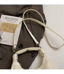 Detail of minimalist cream half-moon leather shoulder bag with adjustable strap