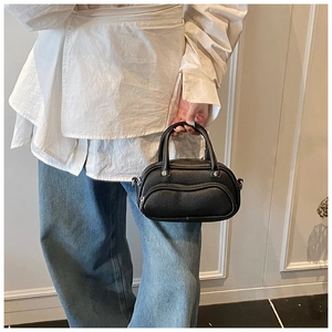 Detail of black lychee grain leather boston bag with dual handles and metal hooks