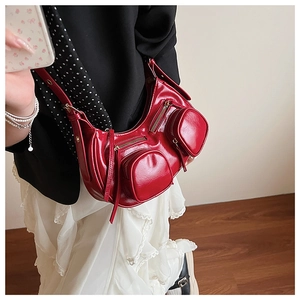 Detailed side view of a red patent leather half-moon bag with biker-style zip pockets
