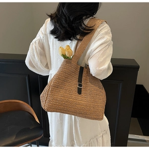 Détail du grand sac cabas en paille avec lanière en cuir noir et boucle en métal argenté