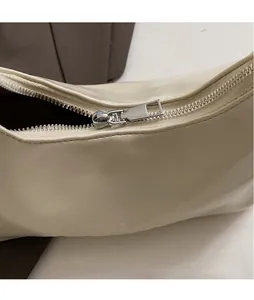 Detail of silver metallic zipper and smooth beige leather texture on the handbag
