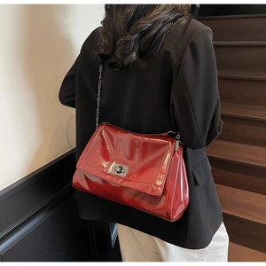 Close-up of glossy red patent leather surface with silver metal twist lock on a tote bag