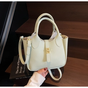 Detail view of mint green pebble leather bucket bag with gold hardware and brand logo