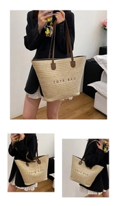 Detail of minimalist straw tote bag with leather handles and printed TOTE BAG text