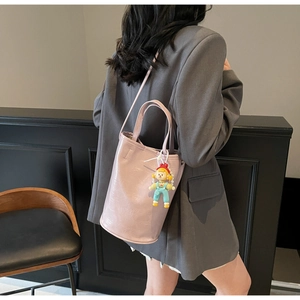 Détail du sac seau rose-violet avec breloque montrant la texture PU et les bandoulières