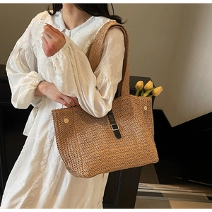 Détail d'un sac cabas en paille tissé main avec boucle en cuir et boutons pression