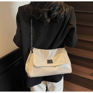 Detail of cream chain bag with metal twist lock and glossy finish on model