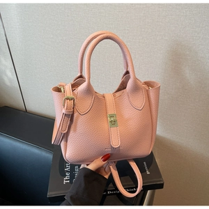 Close-up of pink litchi grain leather handbag with elegant gold metal twist lock detail
