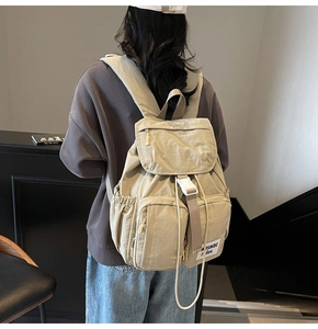 Detail of light khaki nylon backpack with white buckles and drawstring closure