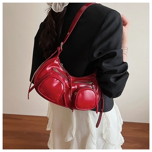 Detail of red patent leather shoulder bag featuring multi-zipper pockets and punk motorcycle style
