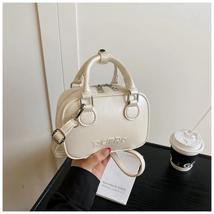Detailed close-up of cream white handbag featuring RETRO embossing and dual metal zippers