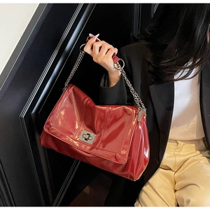 Detail of burgundy patent leather tote bag featuring a metallic twist lock and chain strap
